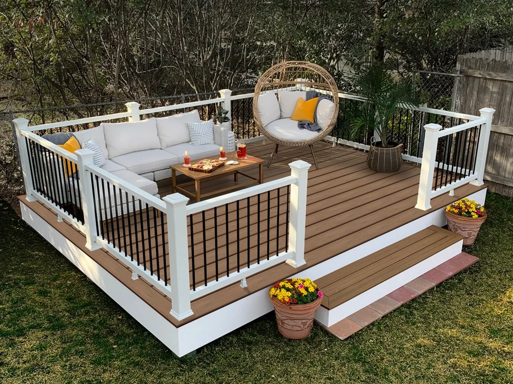 Outdoor deck installation with composite decking, white railing, and modern seating area.