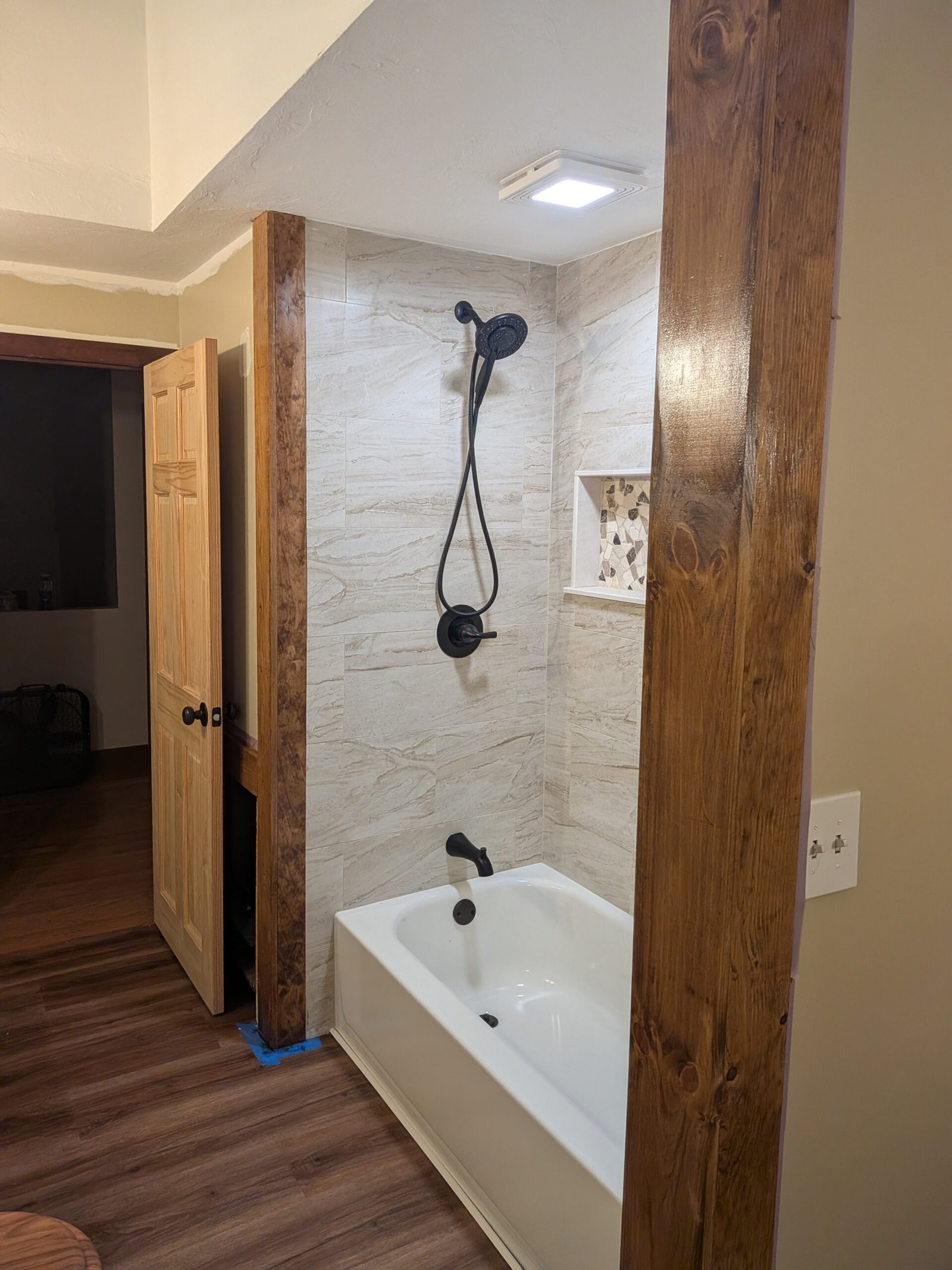 Finished tub and tiled shower surround with custom niche and wood accent beams — bathroom remodel in Hubbardston MA