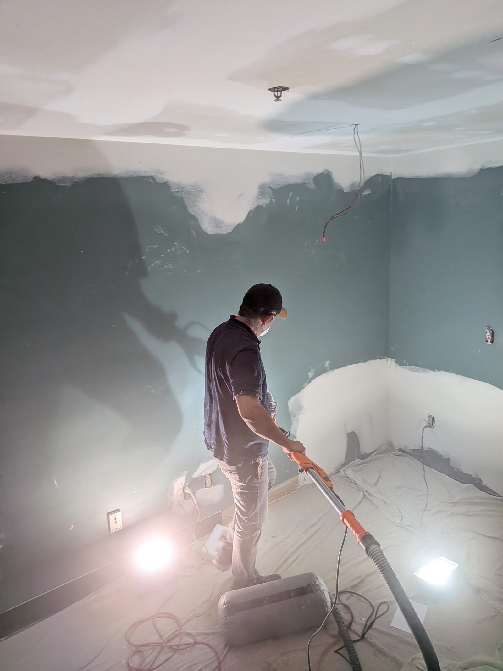 Dust-controlled vacuum sanding during commercial drywall ceiling repair in an occupied building